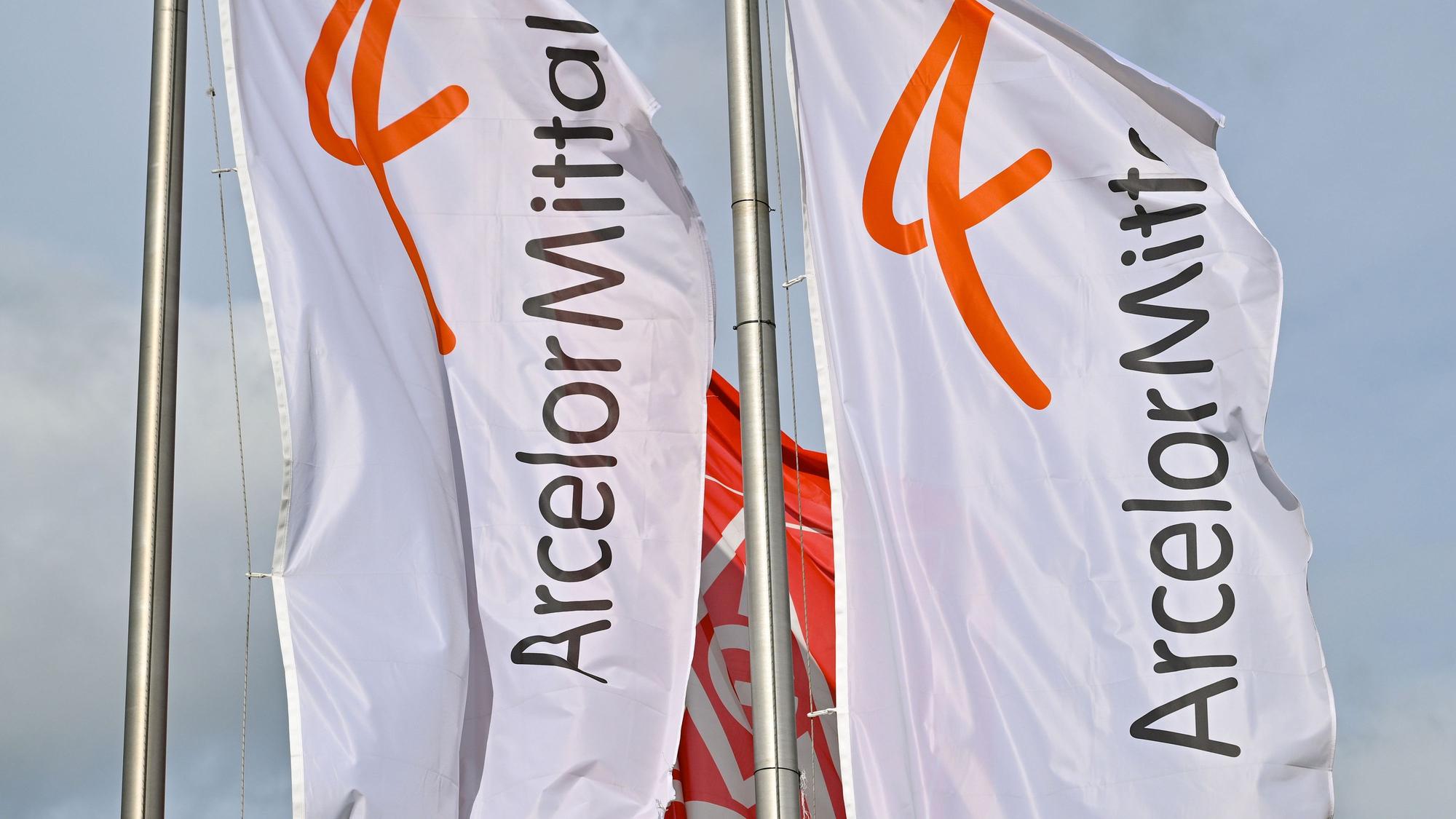 ARCHIV - 14.03.2023, Brandenburg, Eisenhüttenstadt: Fahnen vom Stahlproduzenten ArcelorMittal wehen im Wind. (zu dpa «Für klimaneutrale Stahlproduktion: Aufbau von Wasserstofferzeugung») Foto: Patrick Pleul/dpa +++ dpa-Bildfunk +++