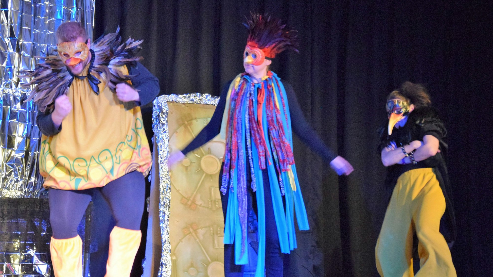 Auf einer Bühne gestikulieren Schauspieler in Vogelkostümen.