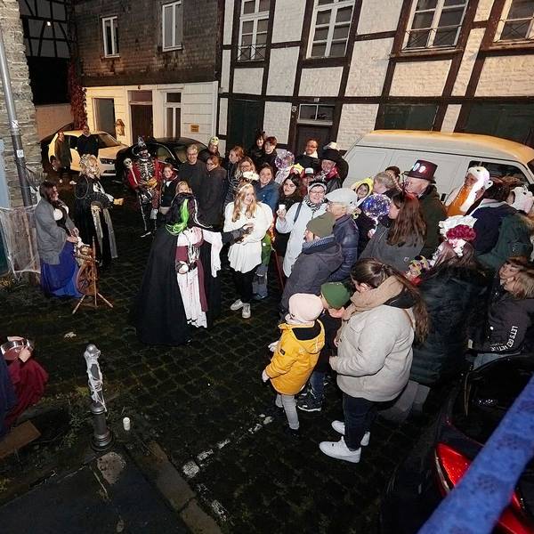 Eine Geisterfigur mit Totenkopf und dunklem Umhang erschreckt Besucher auf der Straße.