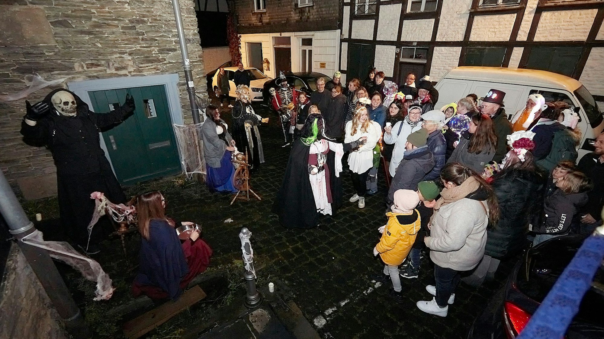 Eine Geisterfigur mit Totenkopf und dunklem Umhang erschreckt Besucher auf der Straße.