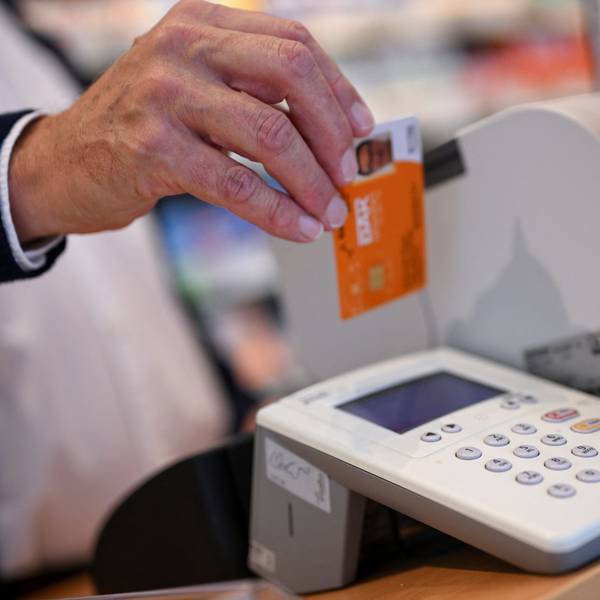 Eine Person legt die Gesundheitskarte eines Patienten in ein Kartenlesegerät in einer Apotheke.