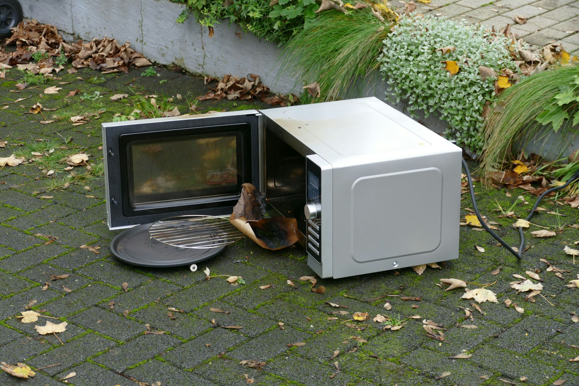 Das Mikrowellengerät, in dem die Brötchen verkohlten, steht draußen auf dem gepflasteren Boden.
