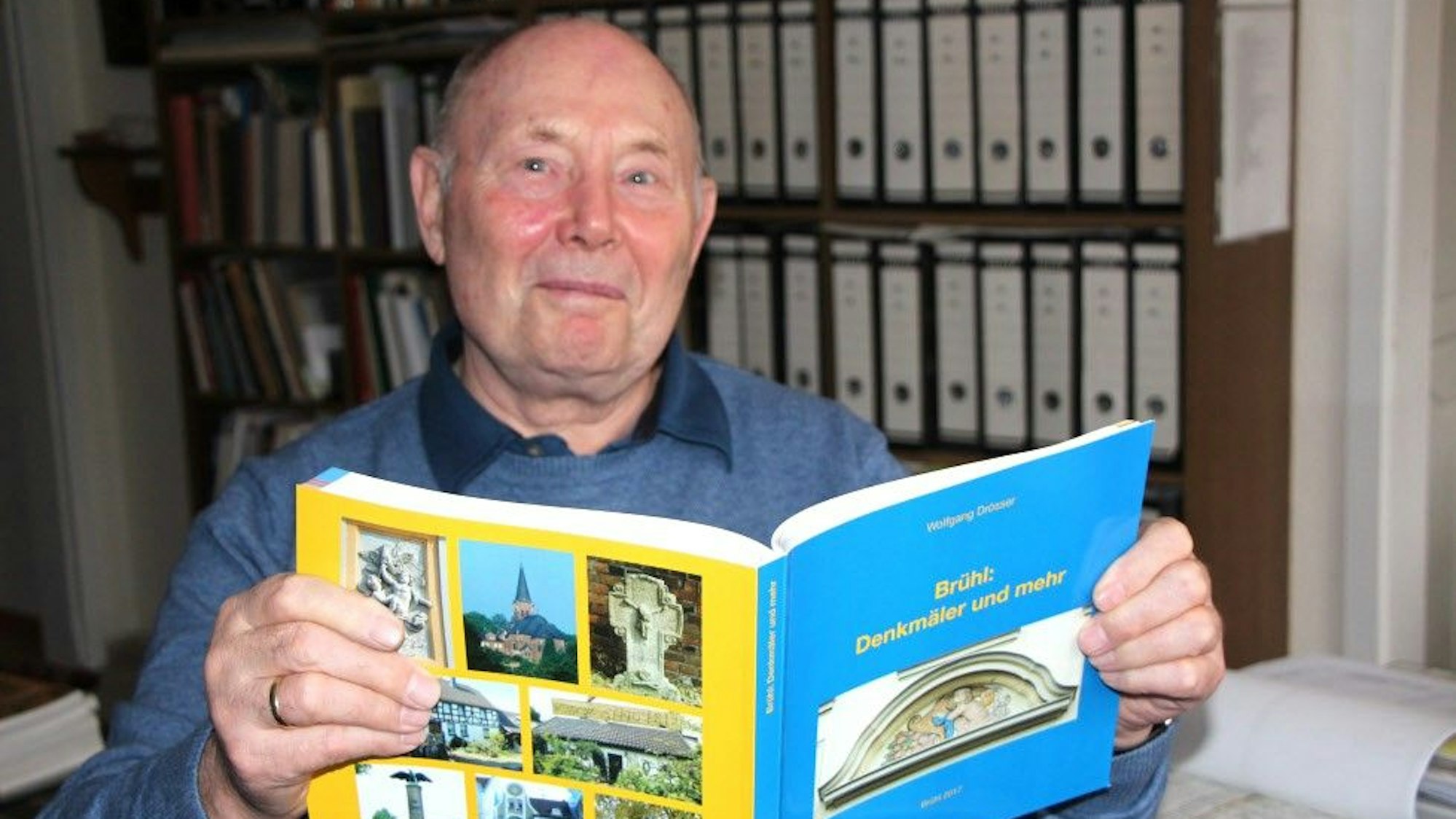 Zu sehen ist Wolfgang Drösser, der eines der selbst verfassten Bücher in den Händen hält.