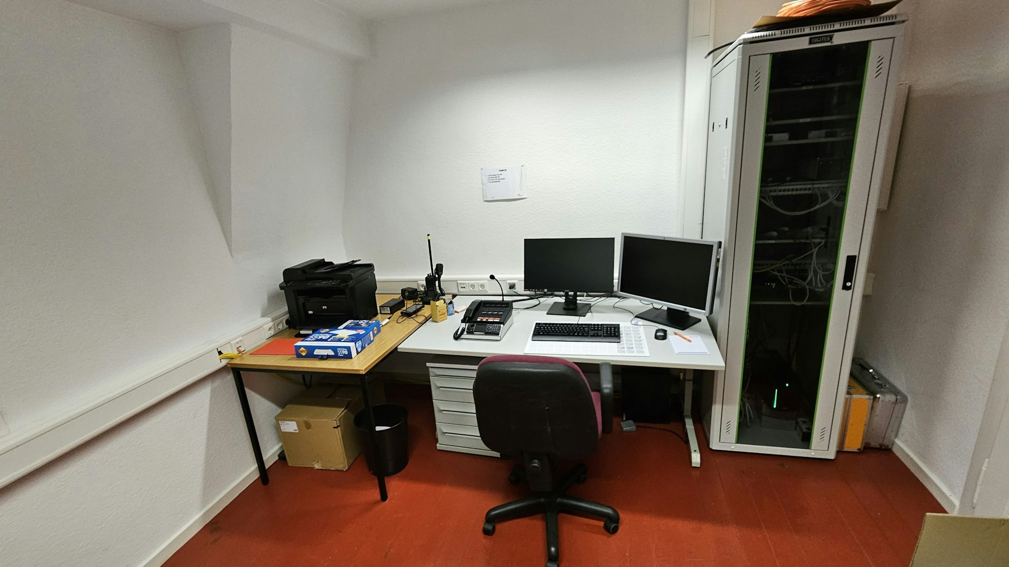 Blick in ein Büro mit Schreibtisch, zwei Bildschirmen und Funkverbindung.