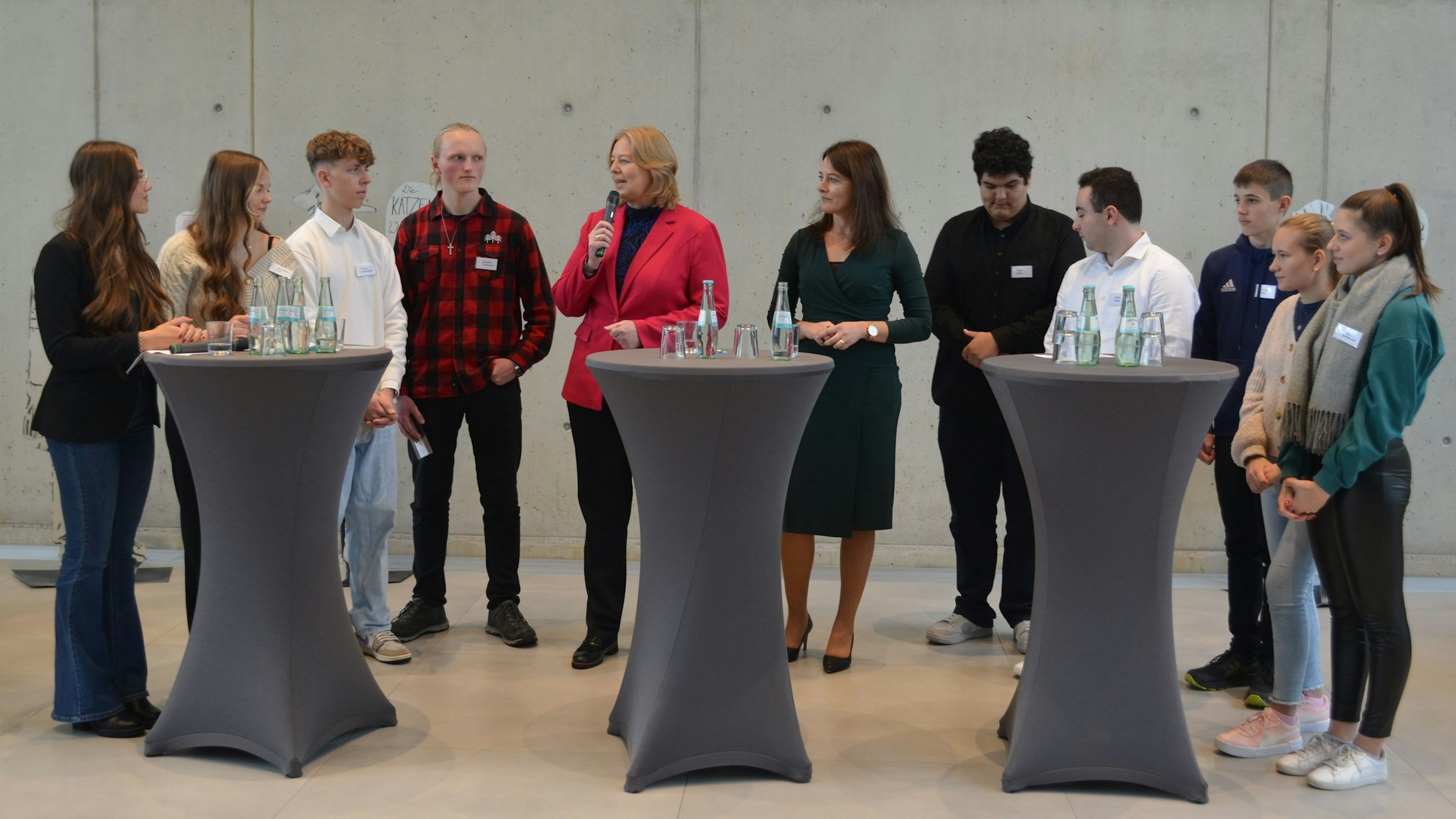 Bundestagspräsidentin Bärbel Bas mit Schülern an Stehpulten.