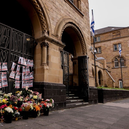 Blumen und Steckbriefe von seit dem Angriff der Hamas Vermissten Israelis hängen an der Synagoge an der Roonstraße in Köln.