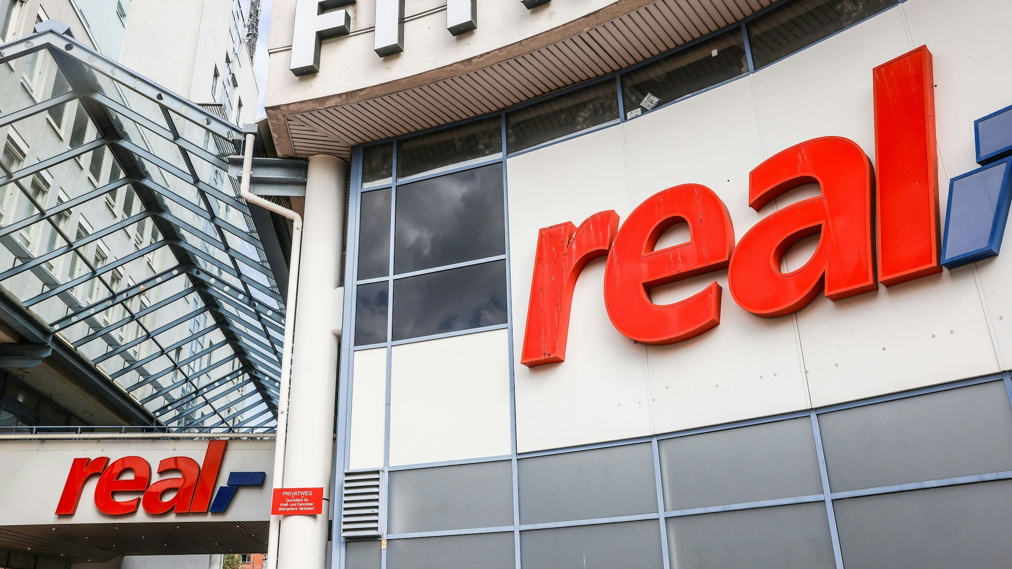 29.09.2023, Nordrhein-Westfalen, Köln: Logos hängen über dem Eingang eines Real Marktes. Die SB-Warenhauskette Mein Real hat nach eigenen Angaben einen Antrag auf Eröffnung eines Insolvenzverfahrens in Eigenverwaltung gestellt.