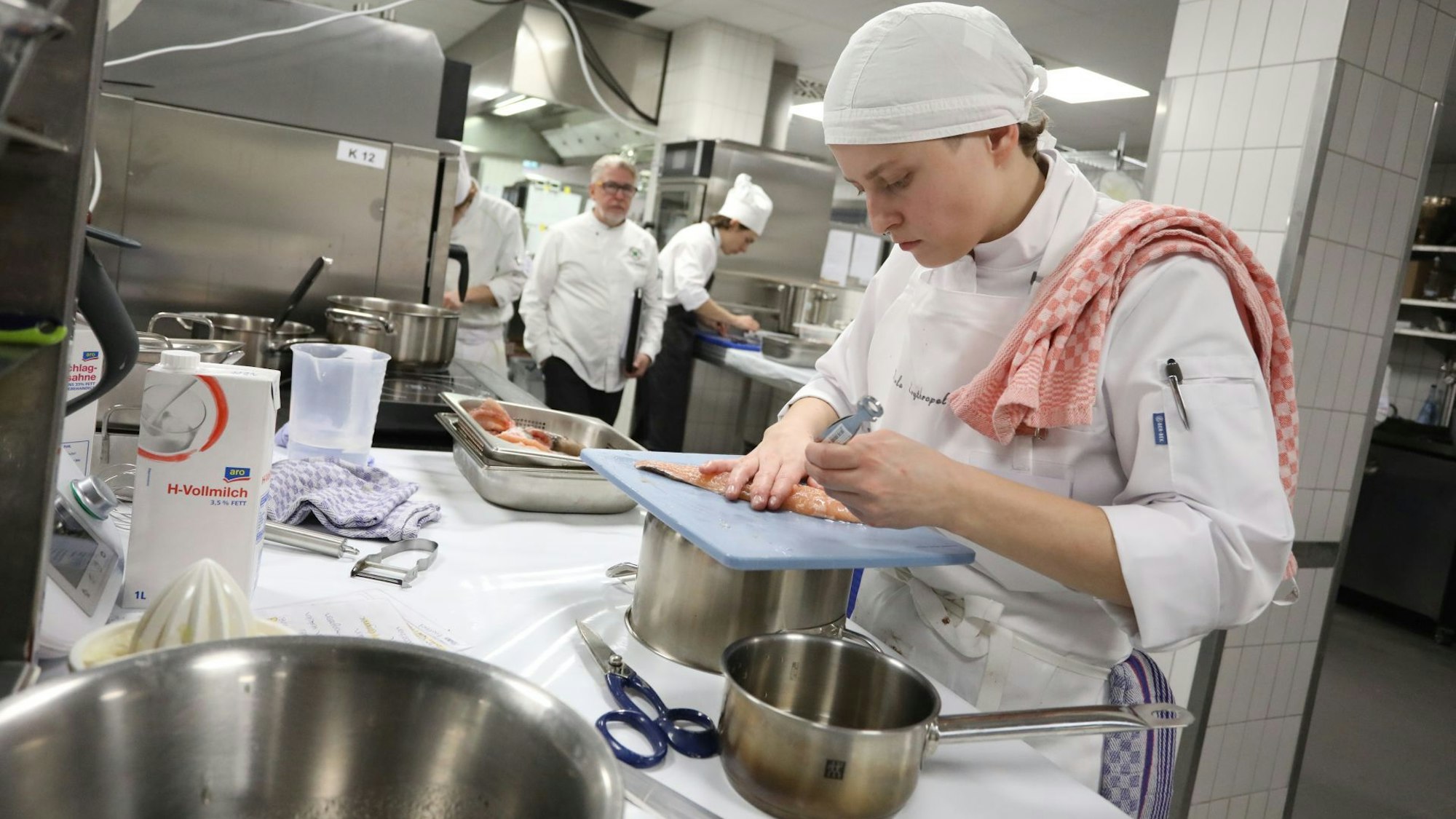 Eine Köchin bereitet den Fisch in der Küche.