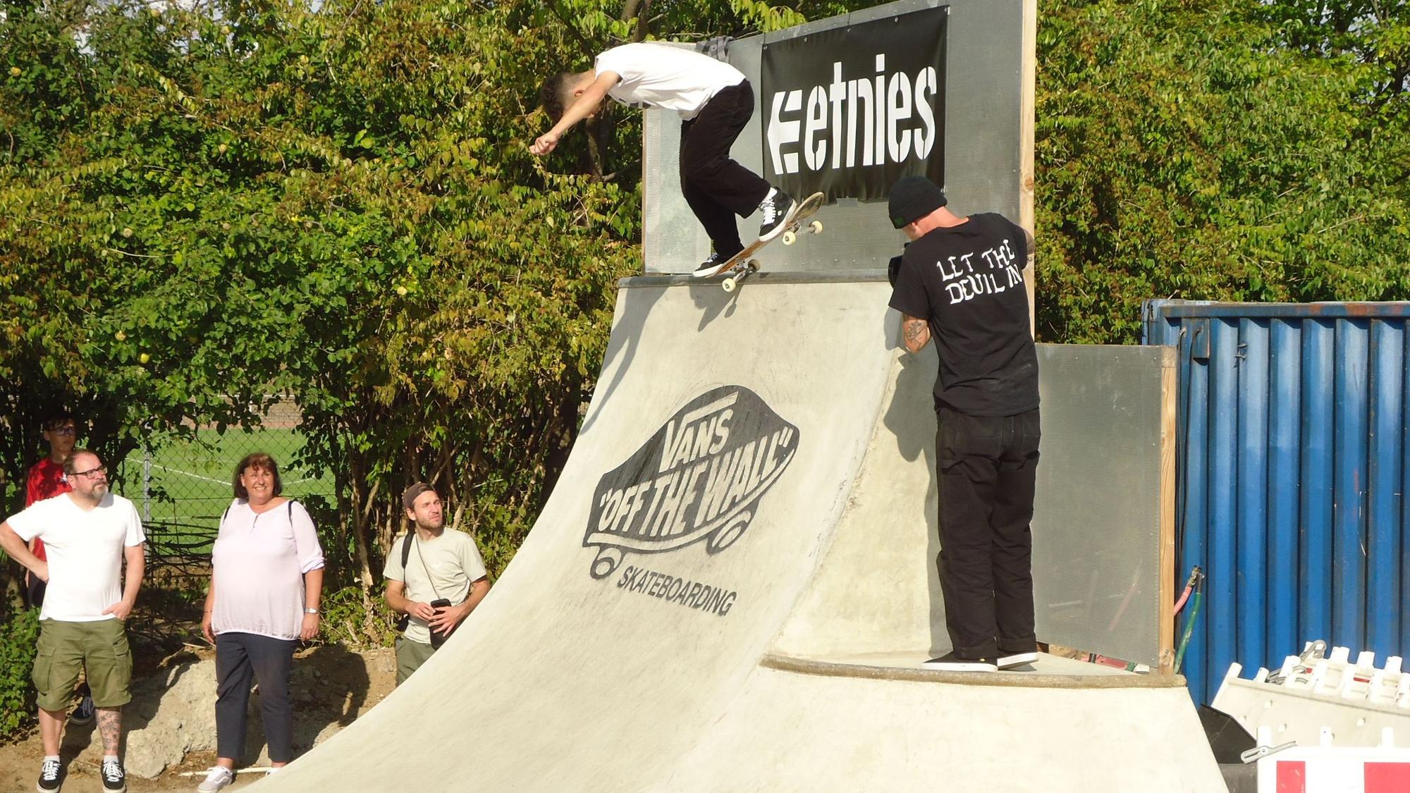 Ein Skateboarder startet auf der Rampe, ein anderer filmt ihn dabei.
