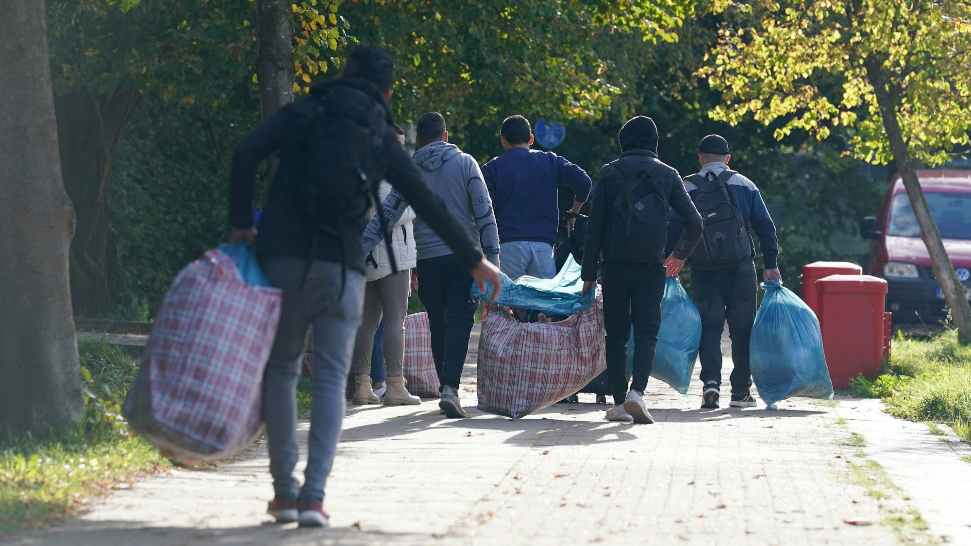Flüchtlinge gehen mit ihrem Gepäck zu der Flüchtlingsunterkunft.