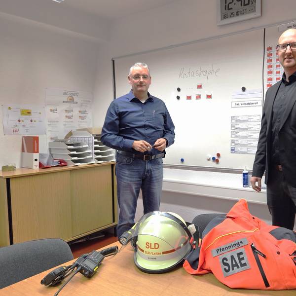 Wolfgang Fuchs (l.), Leiter der Stabsstelle für den Katastrophenschutz, und Bürgermeister Ingo Pfennings stehen vor einer Schreibtafel mit dem Wort Katastrophe.
