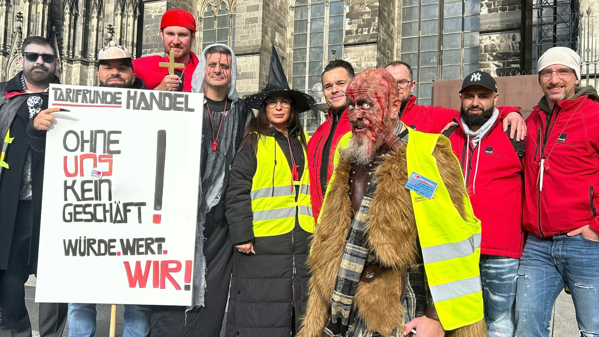 Eine Gruppe Beschäftigter steht in Halloween-Kostümen vor dem Dom.