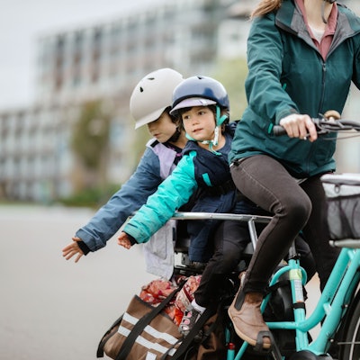 Frau fährt mit zwei Kindern auf dem Fahrrad Foto: Getty Images/RyanJLane