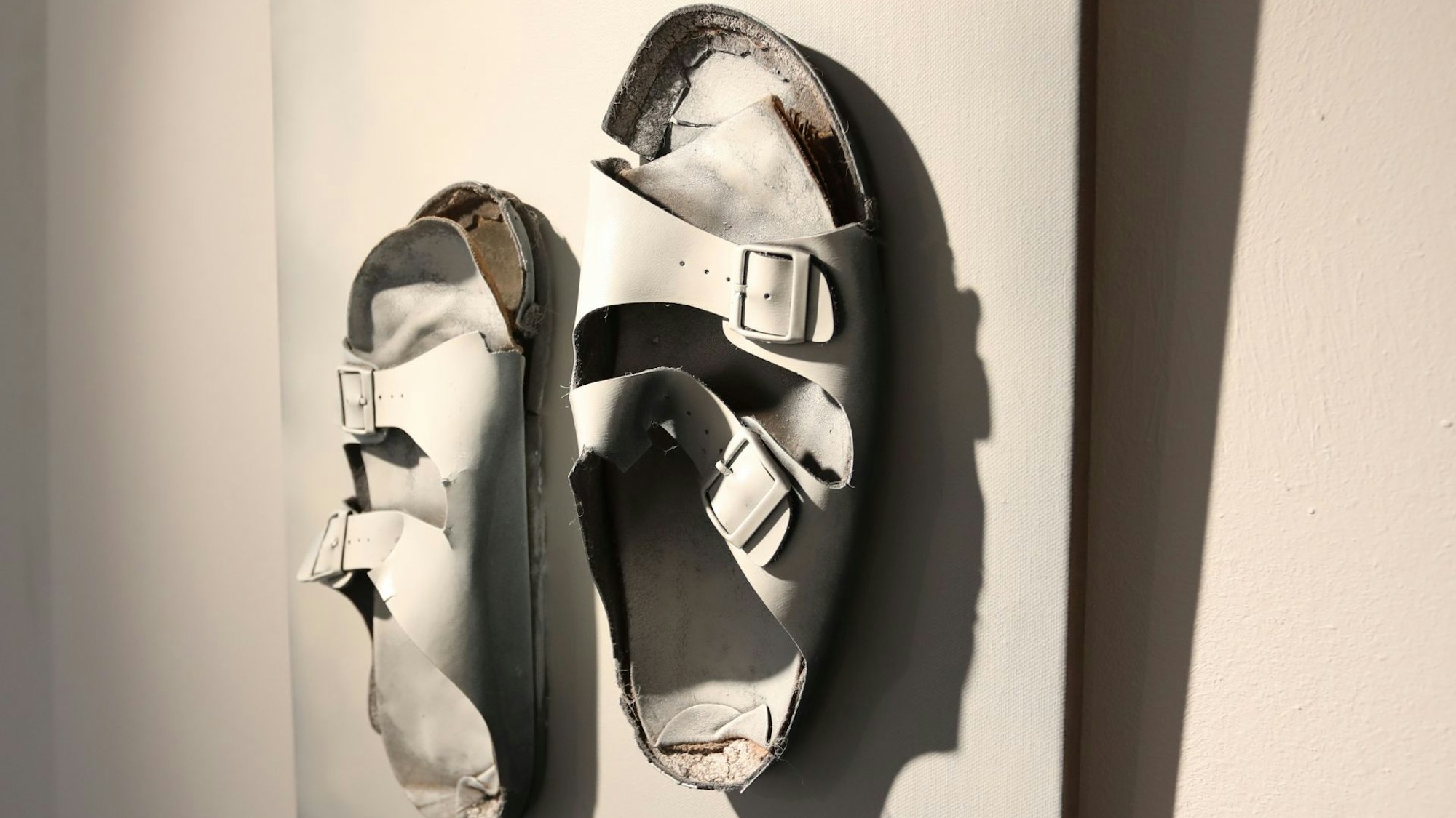 Zwei ausgetretene weiße Sandalen bilden eine Skulptur.