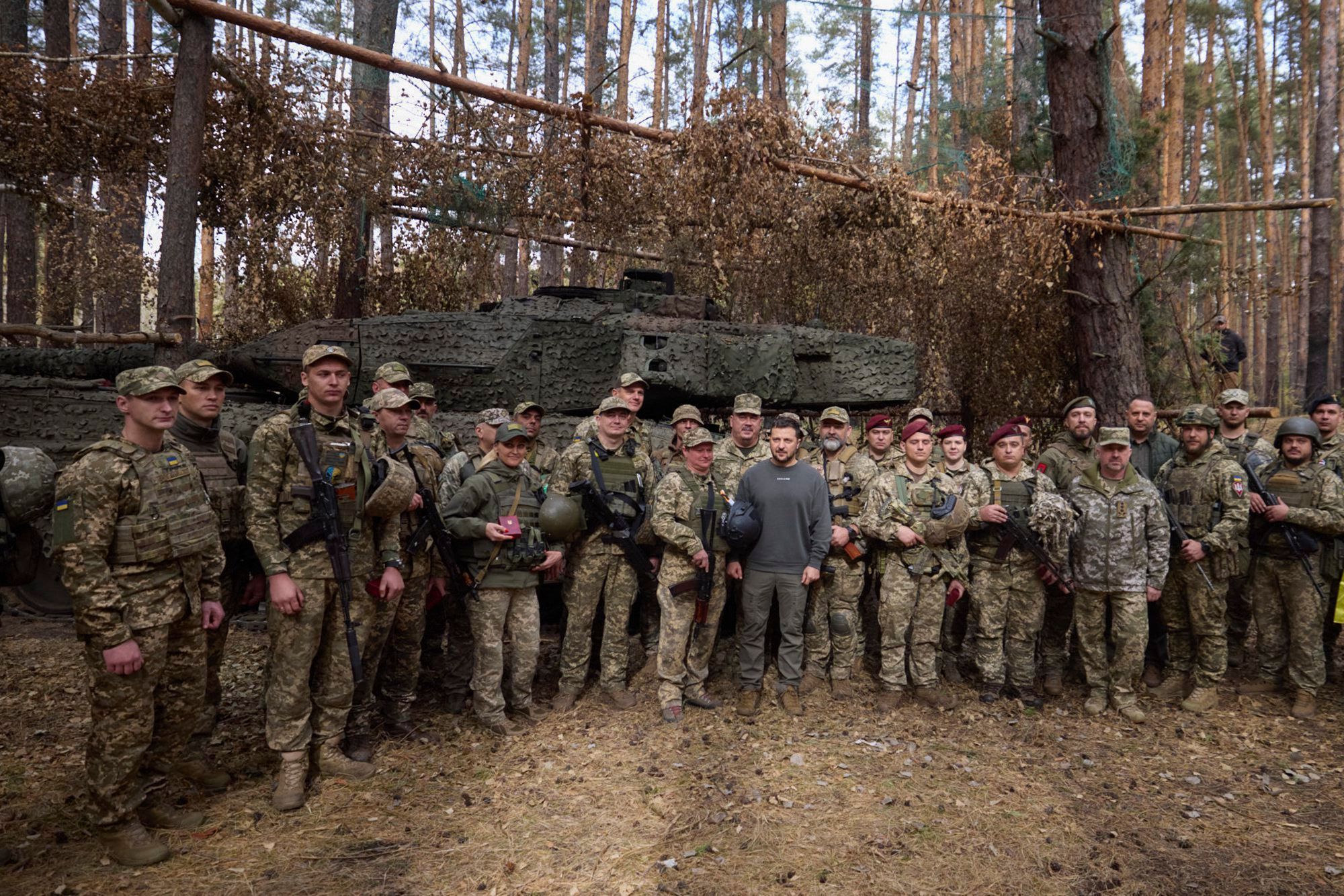 Der ukrainische Präsident Wolodymyr Selenskyj steht Anfang Oktober bei einem Frontbesuch neben ukrainischen Soldaten vor einem Leopard 2-Panzer.
