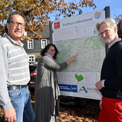 Drei Menschen stehen vor einer Radwegekarte.