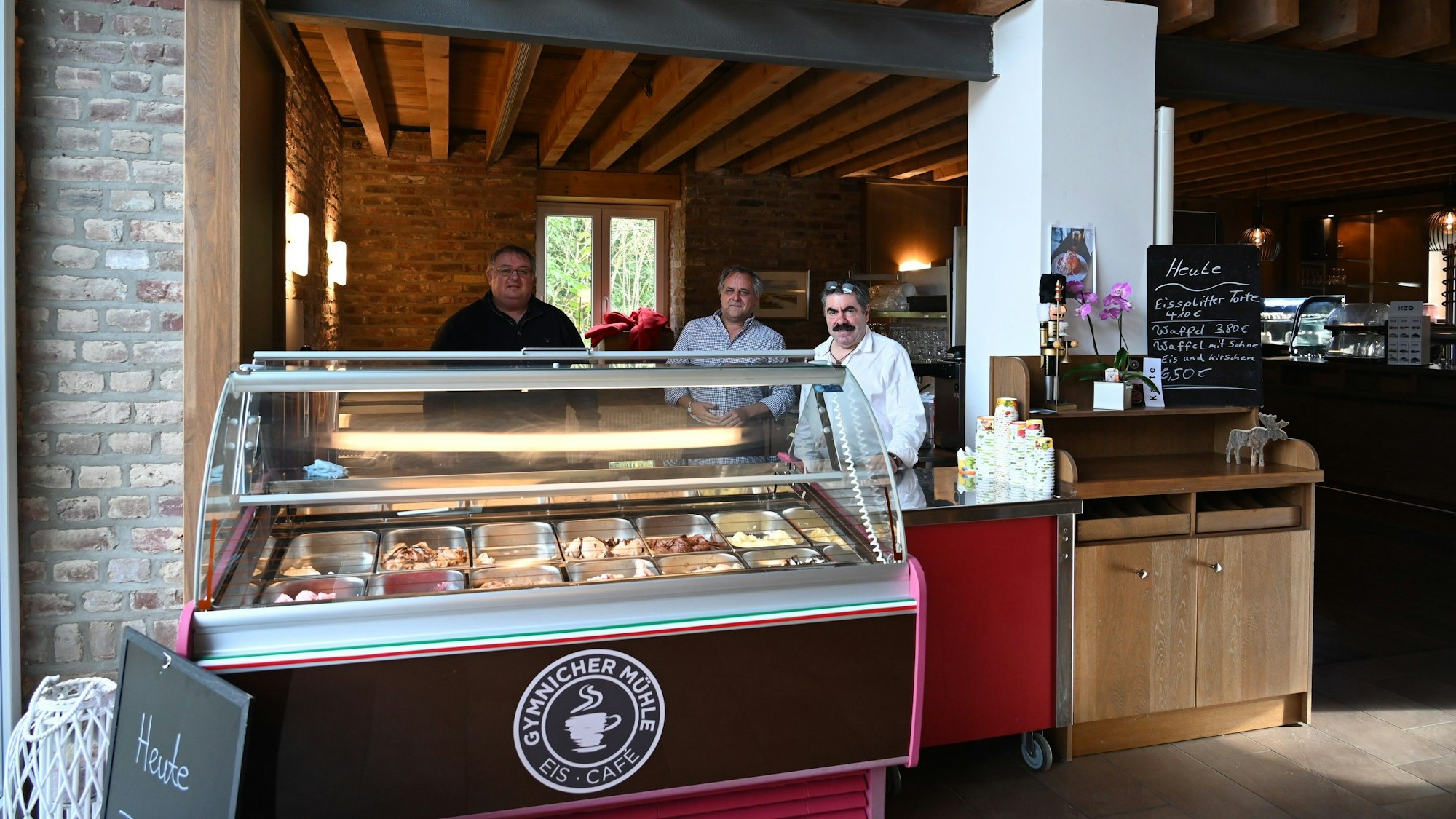 Drei Männer stehen hinter eine Eistheke.