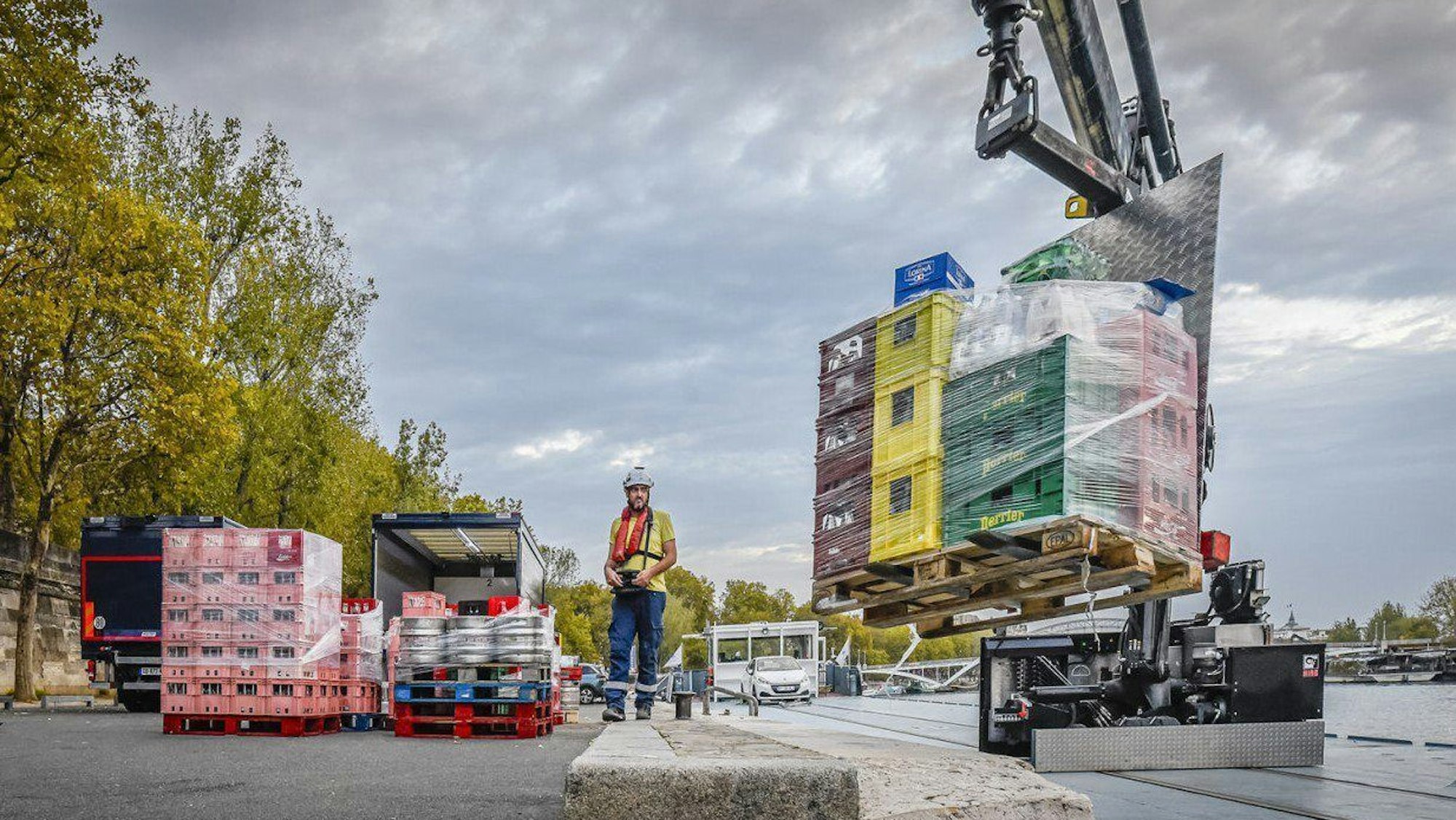HANDOUT - 16.10.2023, Frankreich, Paris: Von einem Schiff werden Getränke mit einem Kran auf einen Kai und von dort in einen Lieferwagen verladen.