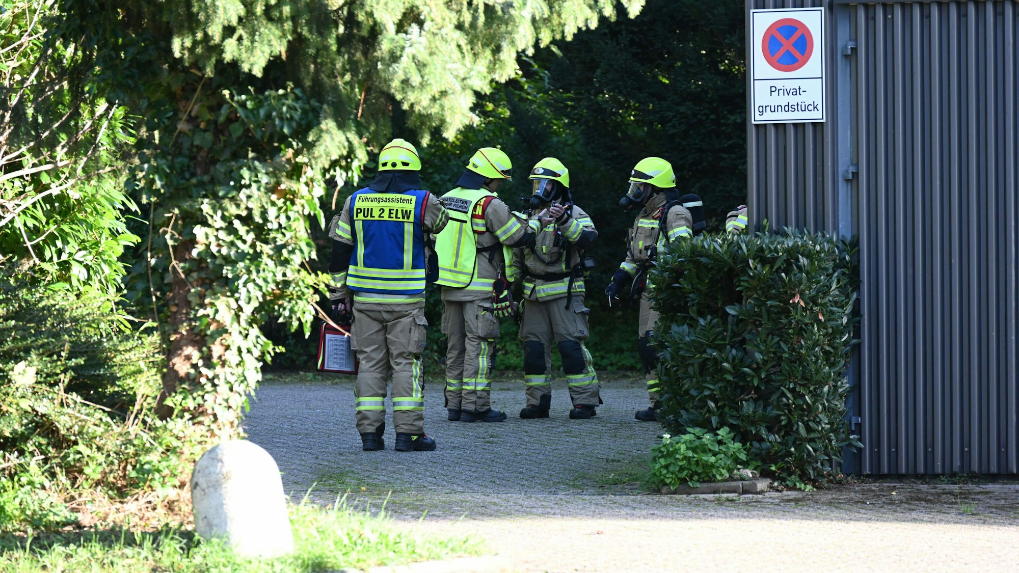 Feuerwehrleute mit Atemschutz stehen an der Tennishalle.