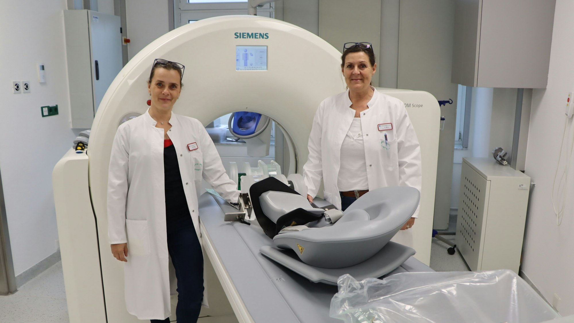 Zwei Frauen stehen an einem medizinischen Großgerät.