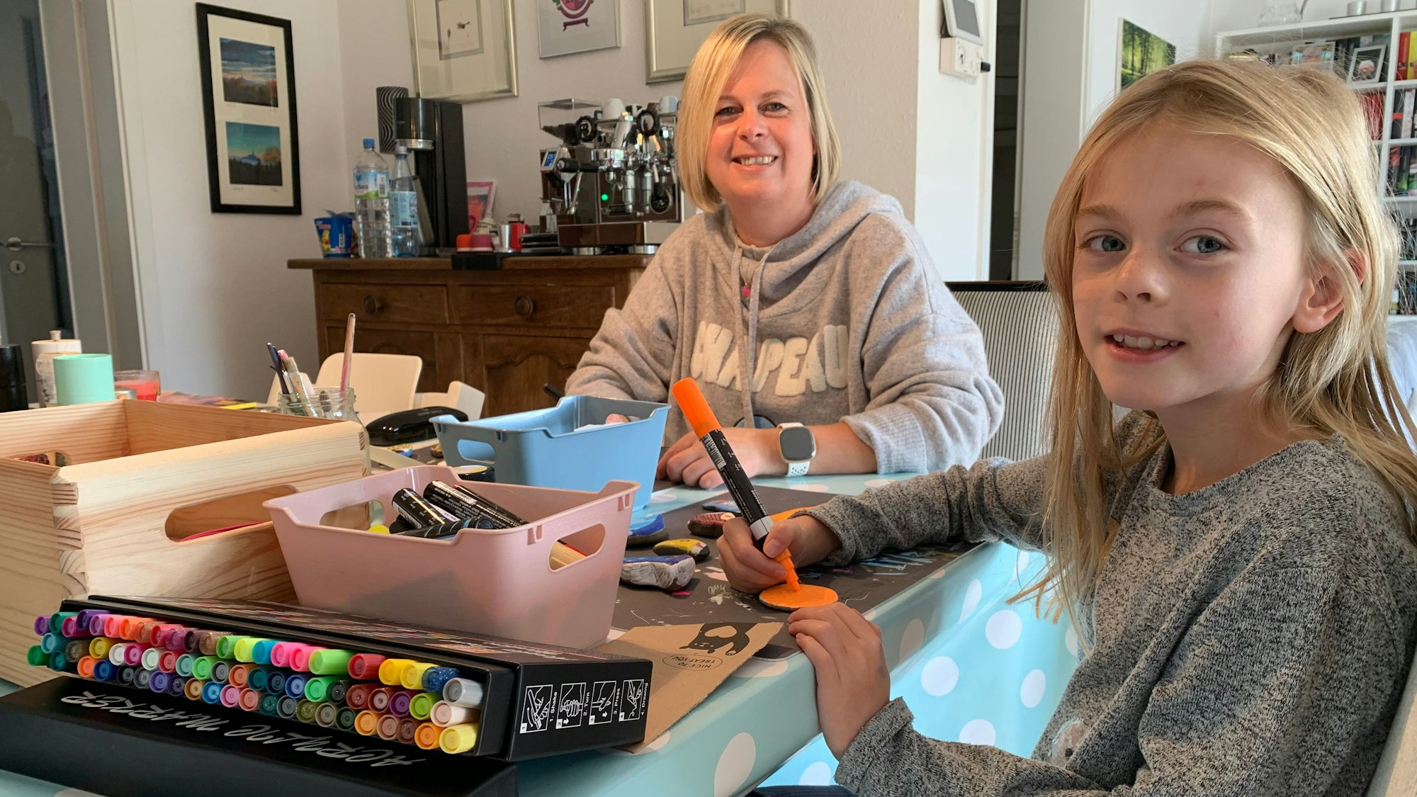 Elisabeth Kochmann bemalt mit Tochter Theresa Steine im Wohnzimmer.
