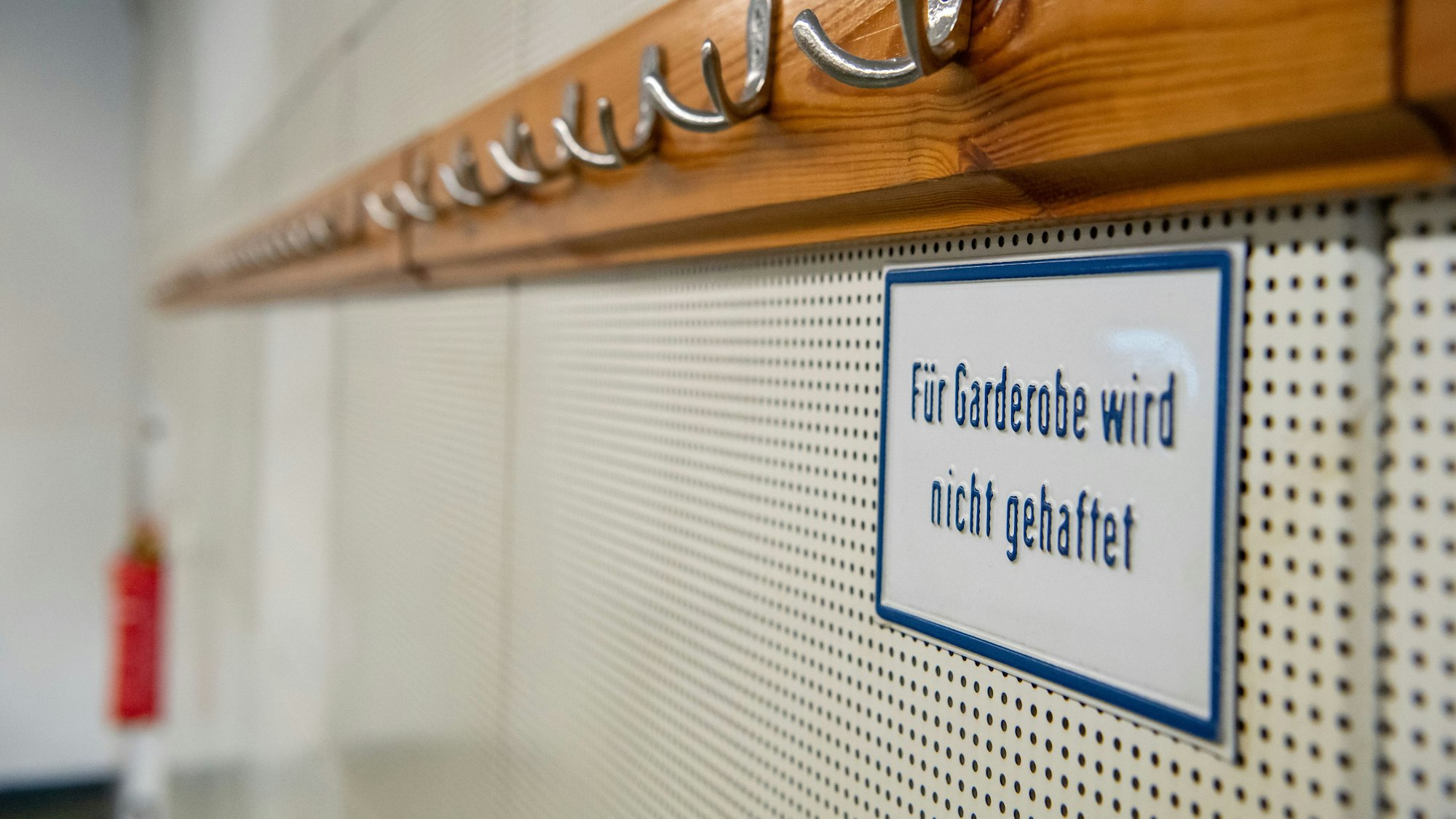 Unter einer leeren Garderobe hängt ein Schild mit der Aufschrift „Für Garderobe wird nicht gehaftet“