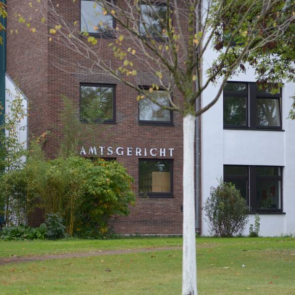 Das Gebäude des Amtsgerichts in Euskirchen, im Vordergrund Sträucher und Bäume.