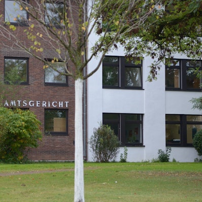 Das Gebäude des Amtsgerichts in Euskirchen, im Vordergrund Sträucher und Bäume.
