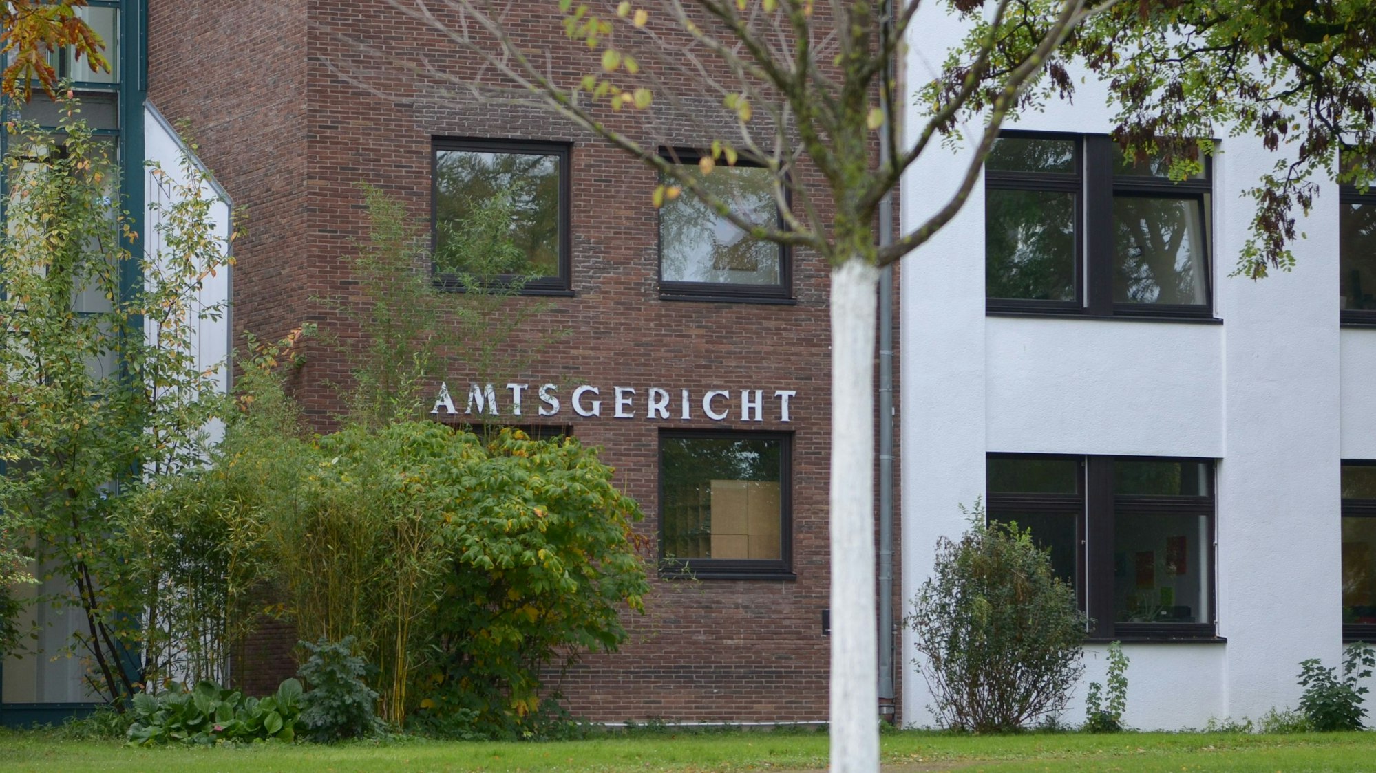 Das Gebäude des Amtsgerichts in Euskirchen, im Vordergrund Sträucher und Bäume.