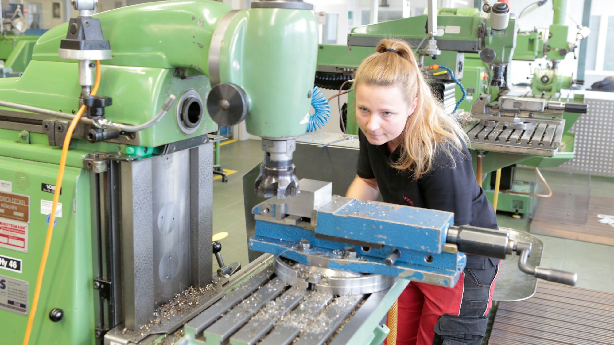 Eine junge Frau stellt eine Fräsmaschine ein.