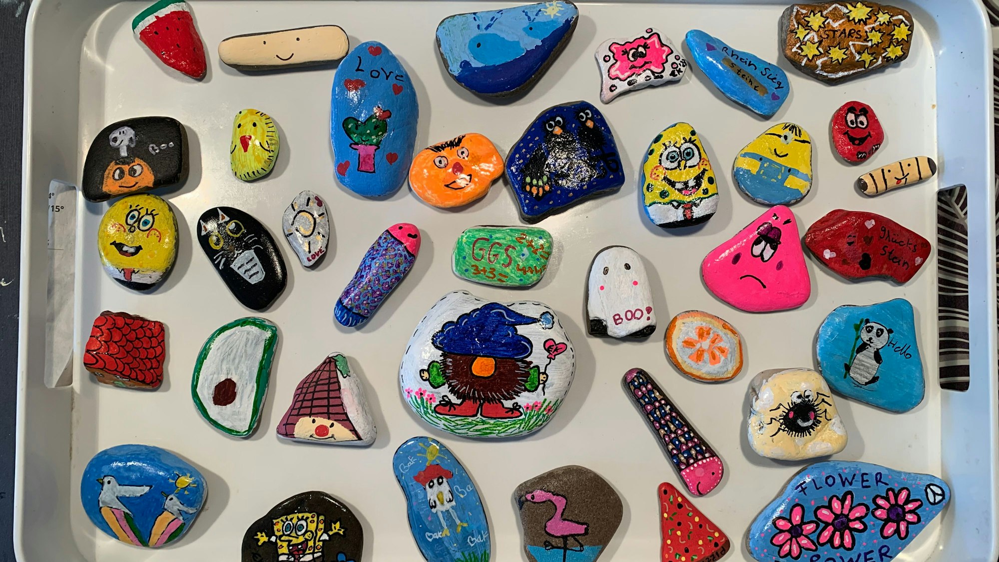 Ein Tablett voller bunt bemalter Steine.