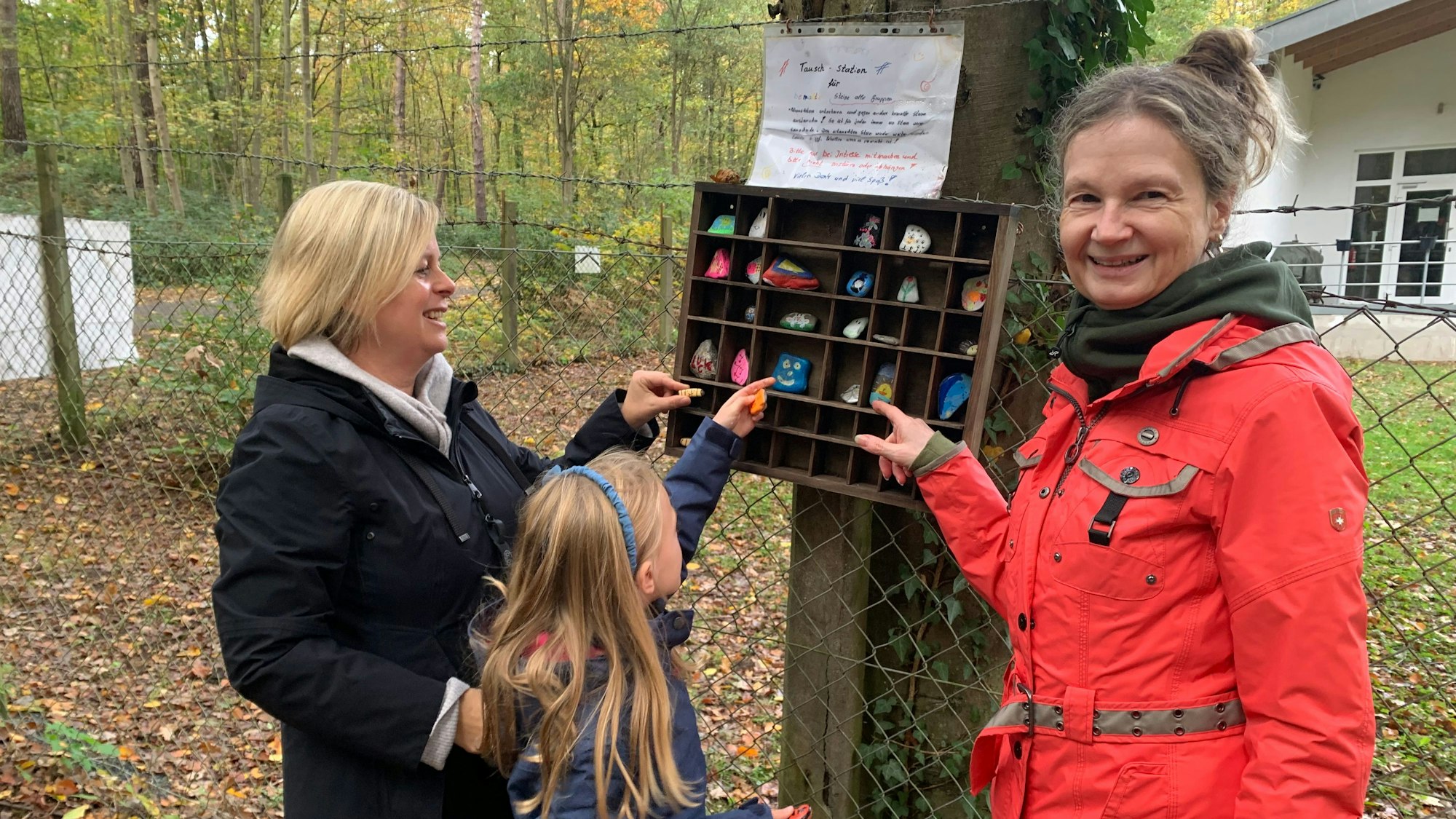 Elisabeth Kochmann legt mit Tochter Theresa Steine in den Setzkasten. Spaziergängerin Michaela Hanke hat den Kasten zufällig entdeckt und ist begeistert von der Idee.