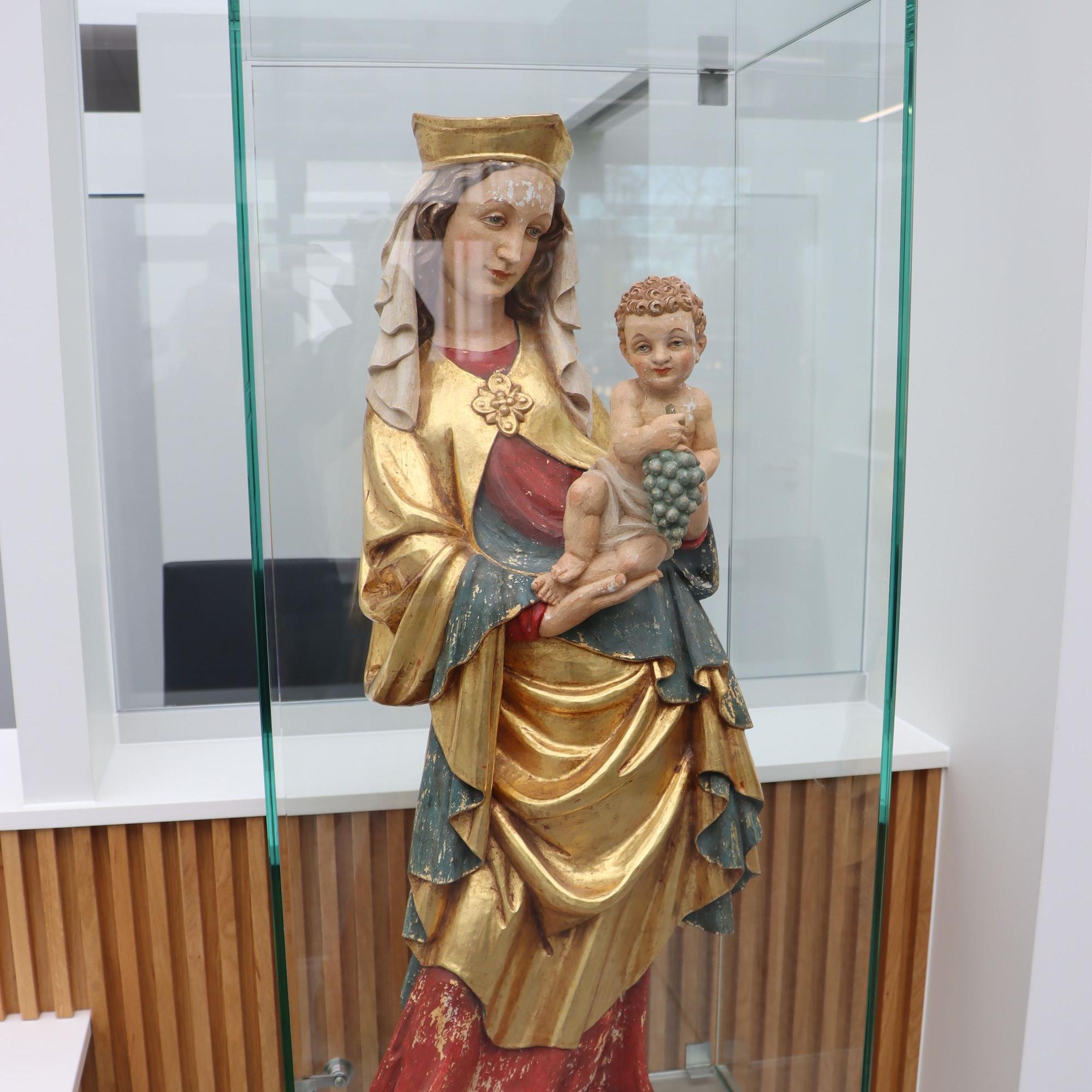 In einer Vitrine steht eine Madonnenfigur.
