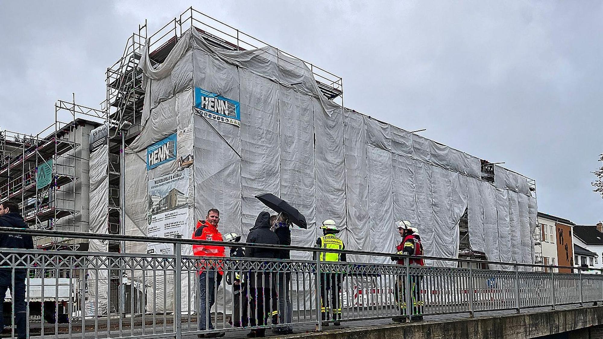 Mehrere Menschen stehen auf einer Brücke vor dem mit einem Gerüst umbauten Johannes-Sturmius-Gymnasium in Schleiden.