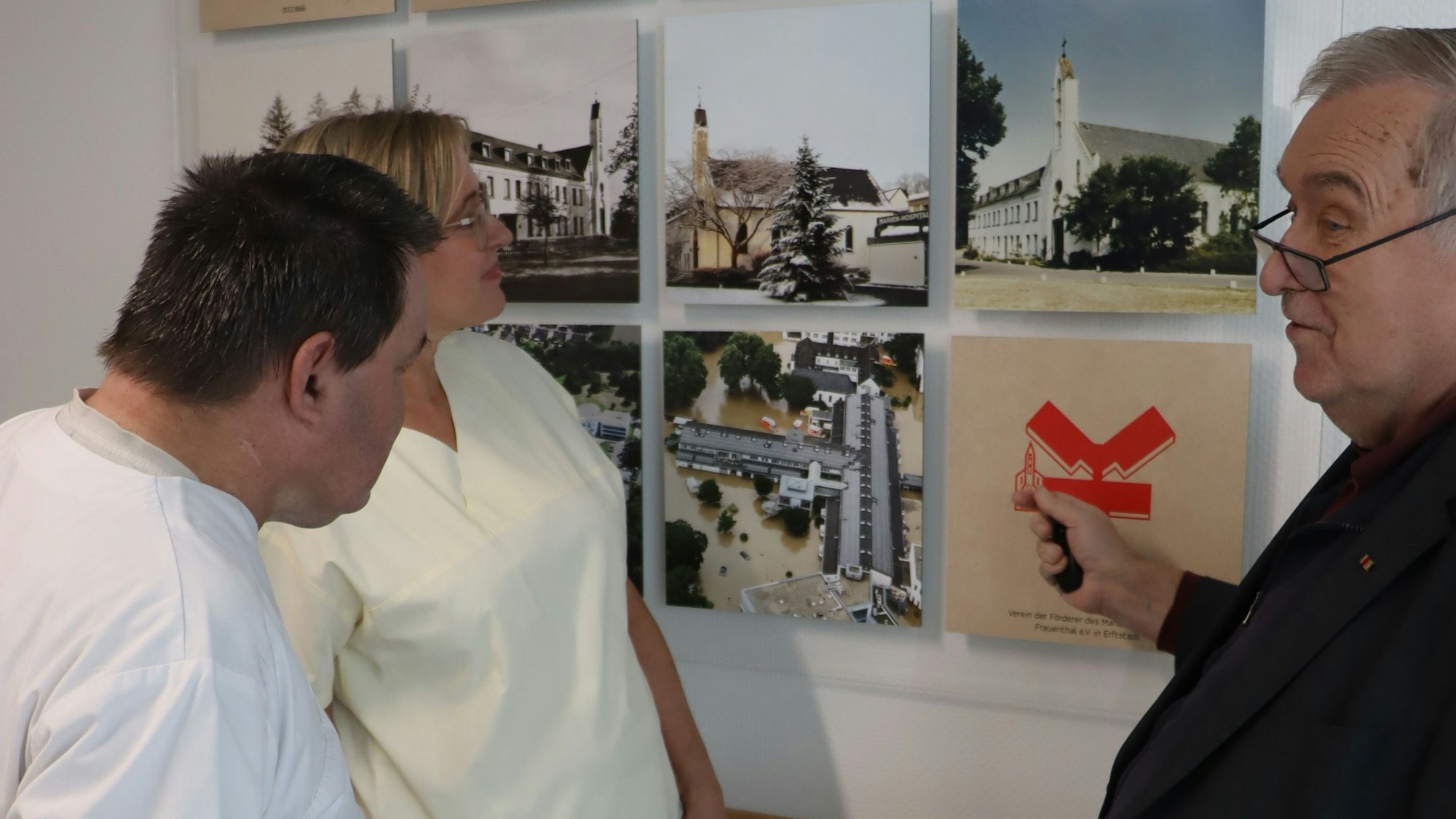 Drei Männer schauen auf eine Fotowand.