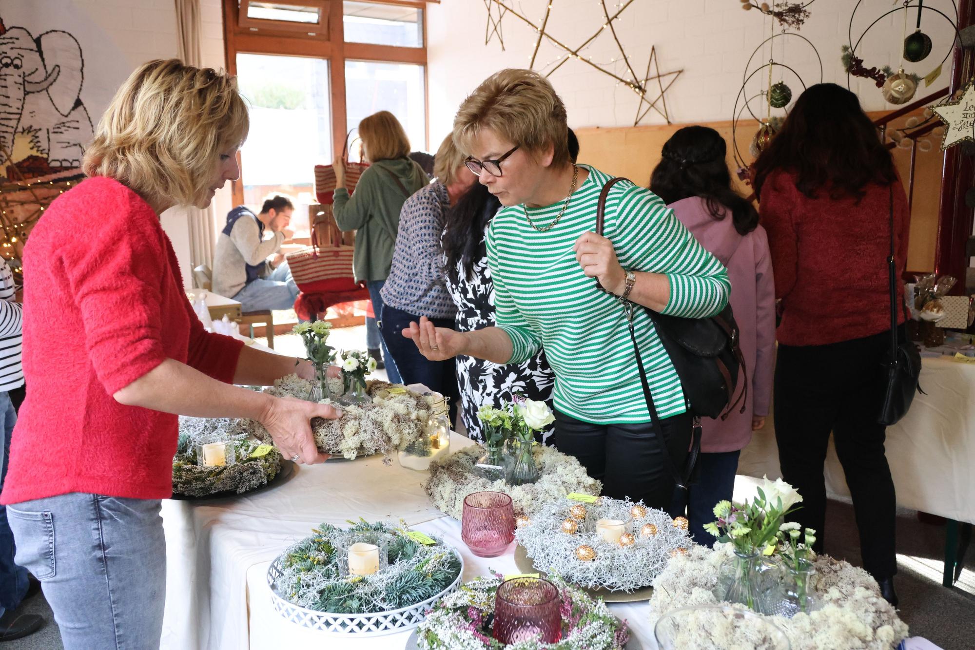 Doris Hartmann steht am Stand von Kerstin Hupperich auf dem Waldbröler Missionsbasar Miba und interessiert sich für einen Adventskranz.