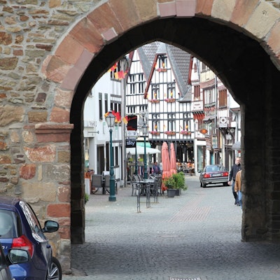 Die Innenstadt von Bad Münstereifel im Jahr 2013, durch das Orchheimer Tor fotografiert. Vor demTor parken Autos. Ein Wagen fährt im Hintergrund über die Orchheimer Straße.