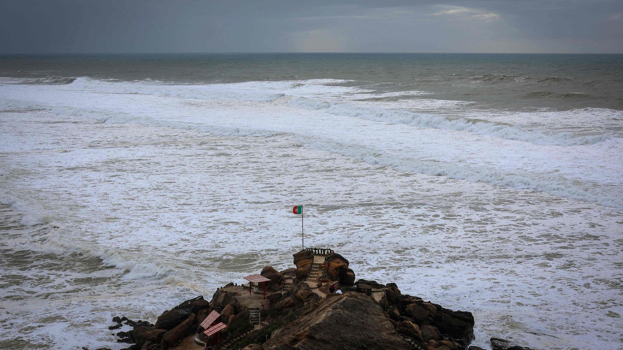 Eine portugiesische Flagge weht auf dem Formosa-Strand vor dem vom Orkan „Ciarán“ aufgewühlten Meer.