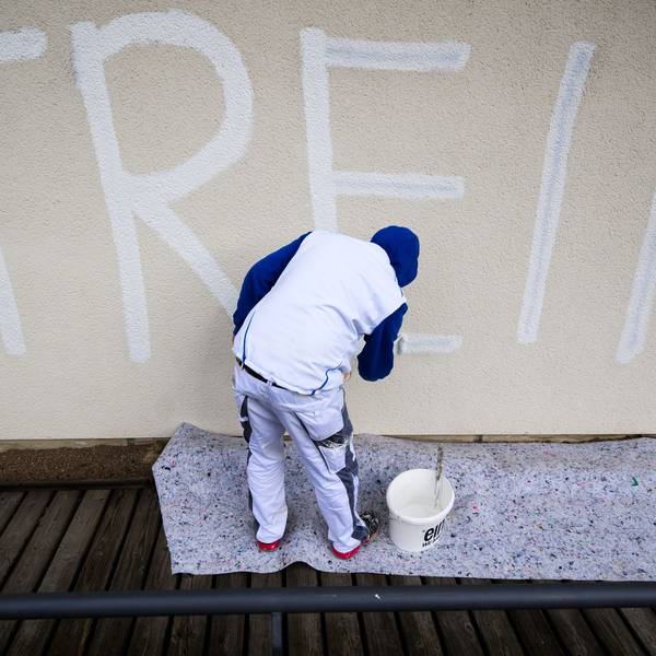 Ein Maler überdeckt am städtischen Nord-Ost-Bad einen schwarzen Schriftzug „Streik“ mit weißer Farbe, um anschließend die komplette Wand flächendeckend neu zu streichen. (Archivbild)