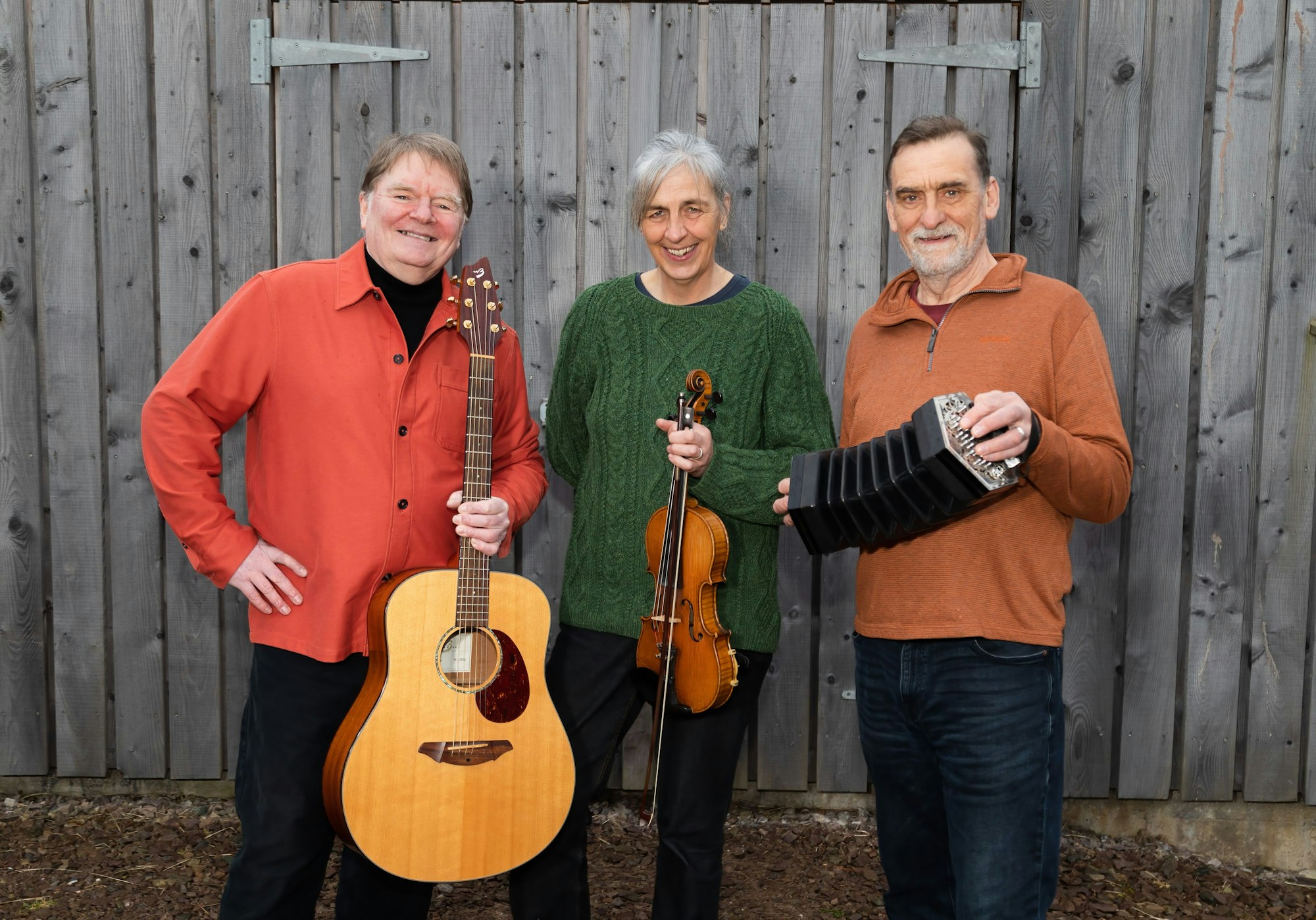 Die drei Musiker der Band Scaladal posieren vor einer Holzwand.