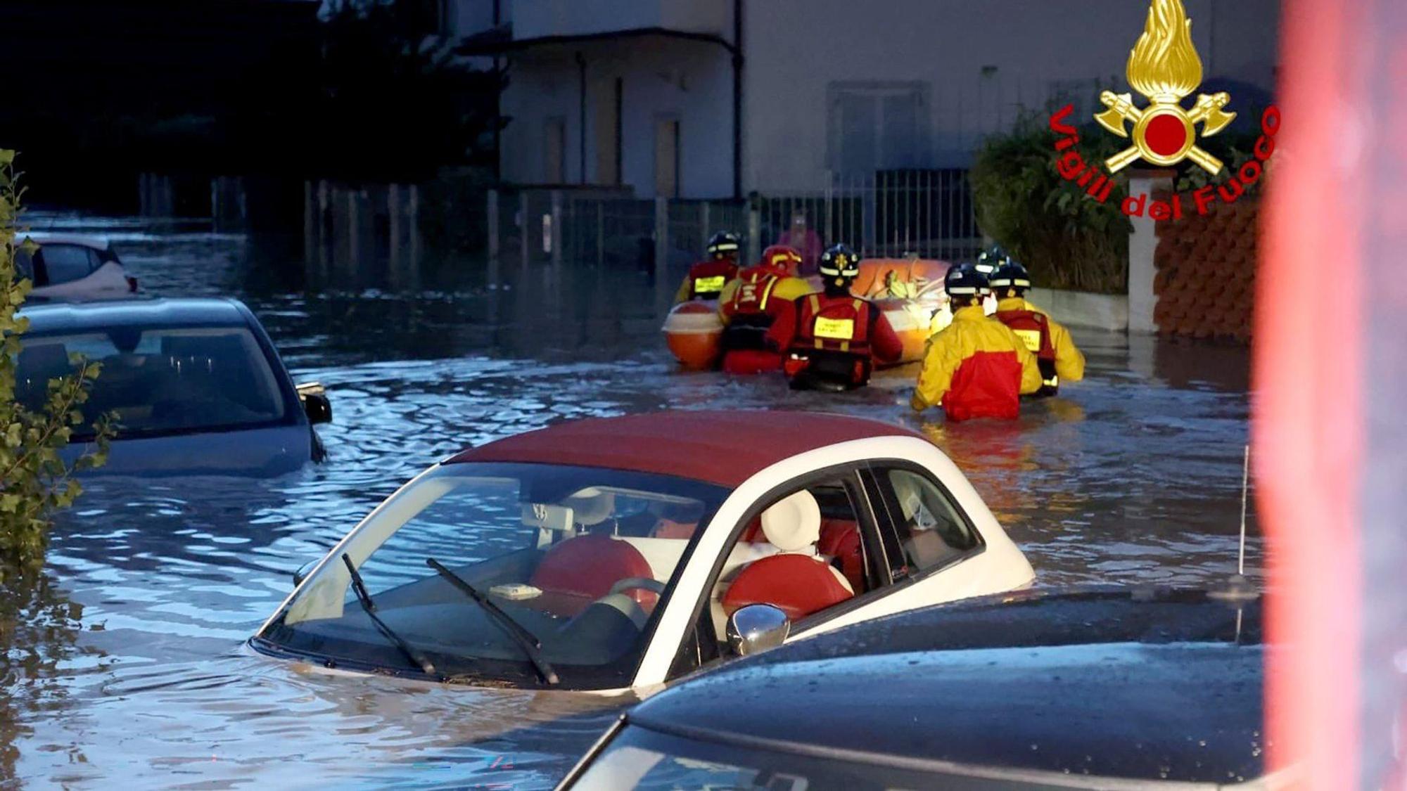 HANDOUT - 03.11.2023, Italien, Lamporecchio: Feuerwehrleute schieben ein Schlauchboot durch eine überschwemmte Straße, in der zahlreiche Autos unter Wasser stehen. Schwere Unwetter mit heftigen Regenfällen haben die mittelitalienische Region Toskana in der Nacht zum Freitag heimgesucht. Foto: -/Vigili del Fuoco/dpa - ACHTUNG: Nur zur redaktionellen Verwendung im Zusammenhang mit der aktuellen Berichterstattung und nur mit vollständiger Nennung des vorstehenden Credits +++ dpa-Bildfunk +++