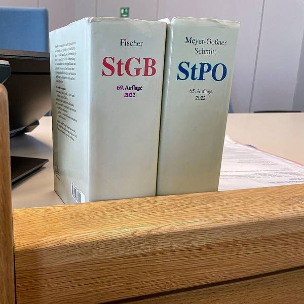 Das Bild zeigt Gesetzbücher auf dem Richtertisch eines Gerichts.