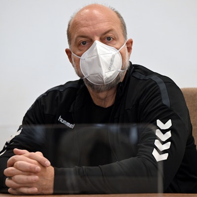 Thomas Drach sitzt mit Mundschutz auf einem Stuhl.