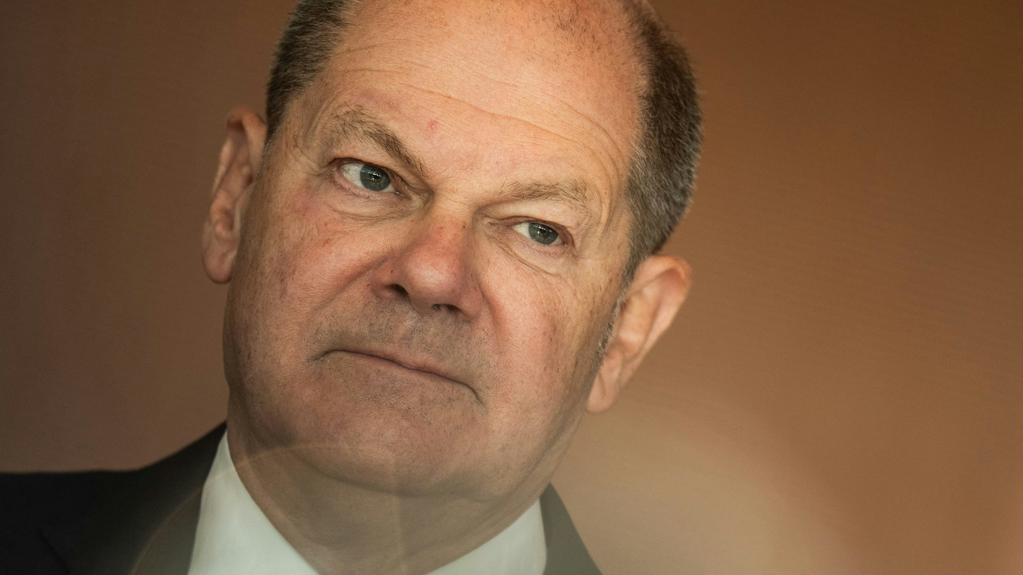 Nahaufnahme des Gesichts von Bundeskanzler Olaf Scholz (SPD) mit Linseneffekt am unteren Bildrand