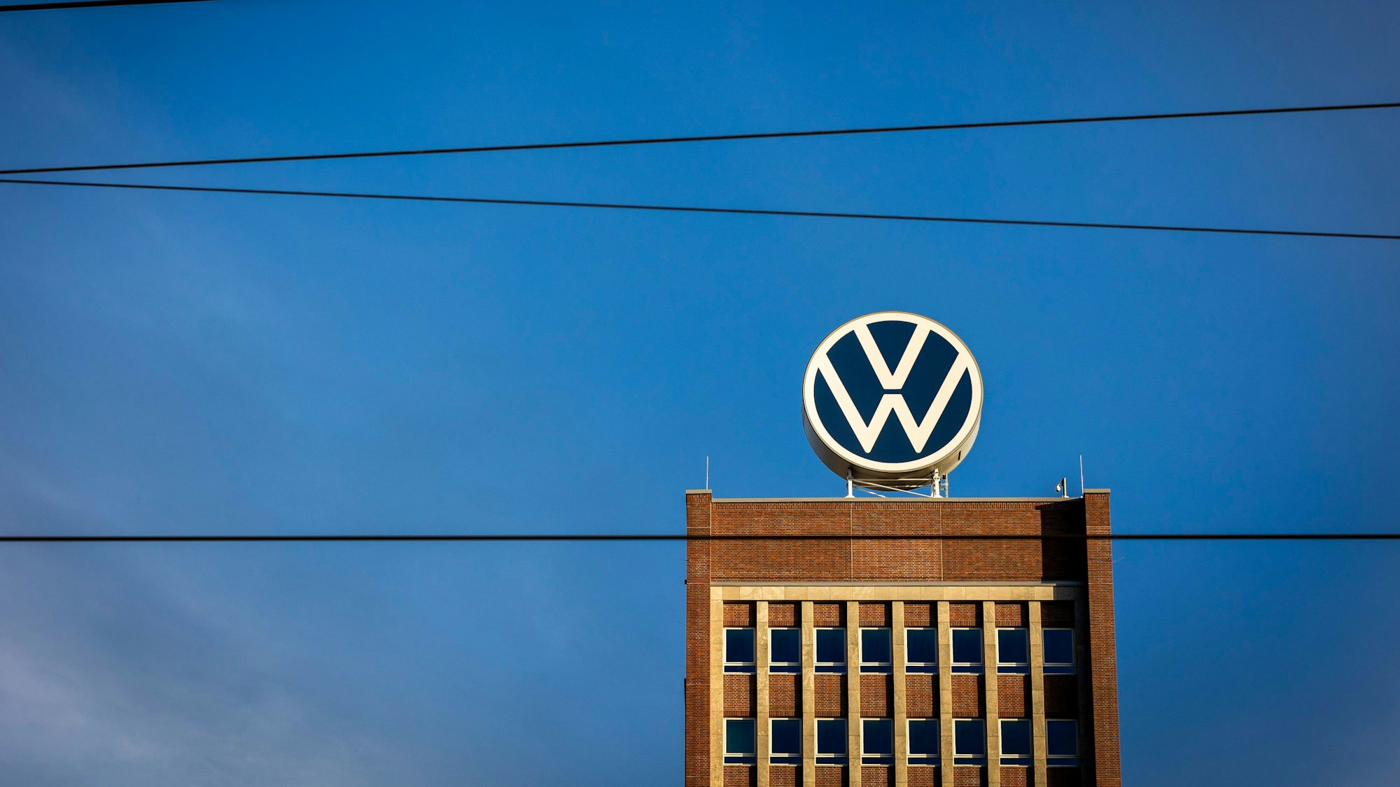 ARCHIV - 28.09.2023, Niedersachsen, Wolfsburg: Das Markenhochhaus im Volkswagen Stammwerk ist am Morgen hinter Leitungen einer Bahnstrecke zu sehen. Volkswagen gibt am 26.10.2023 Zahlen für das 3. Quartal bekannt. Foto: Moritz Frankenberg/dpa +++ dpa-Bildfunk +++