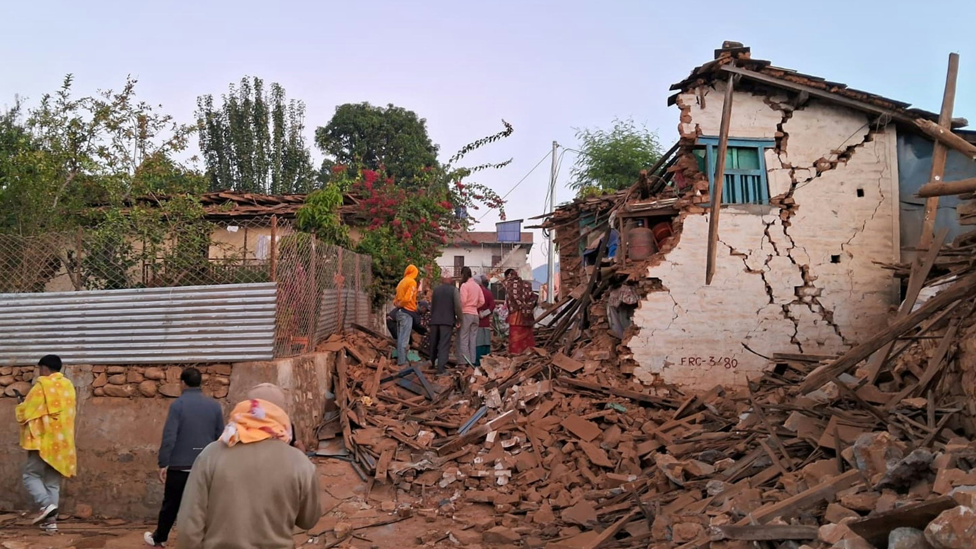 Menschen schauen auf die Trümmer eines Hauses nach dem schweren Erdbeben in Nepal am Samstag, 4. November.
