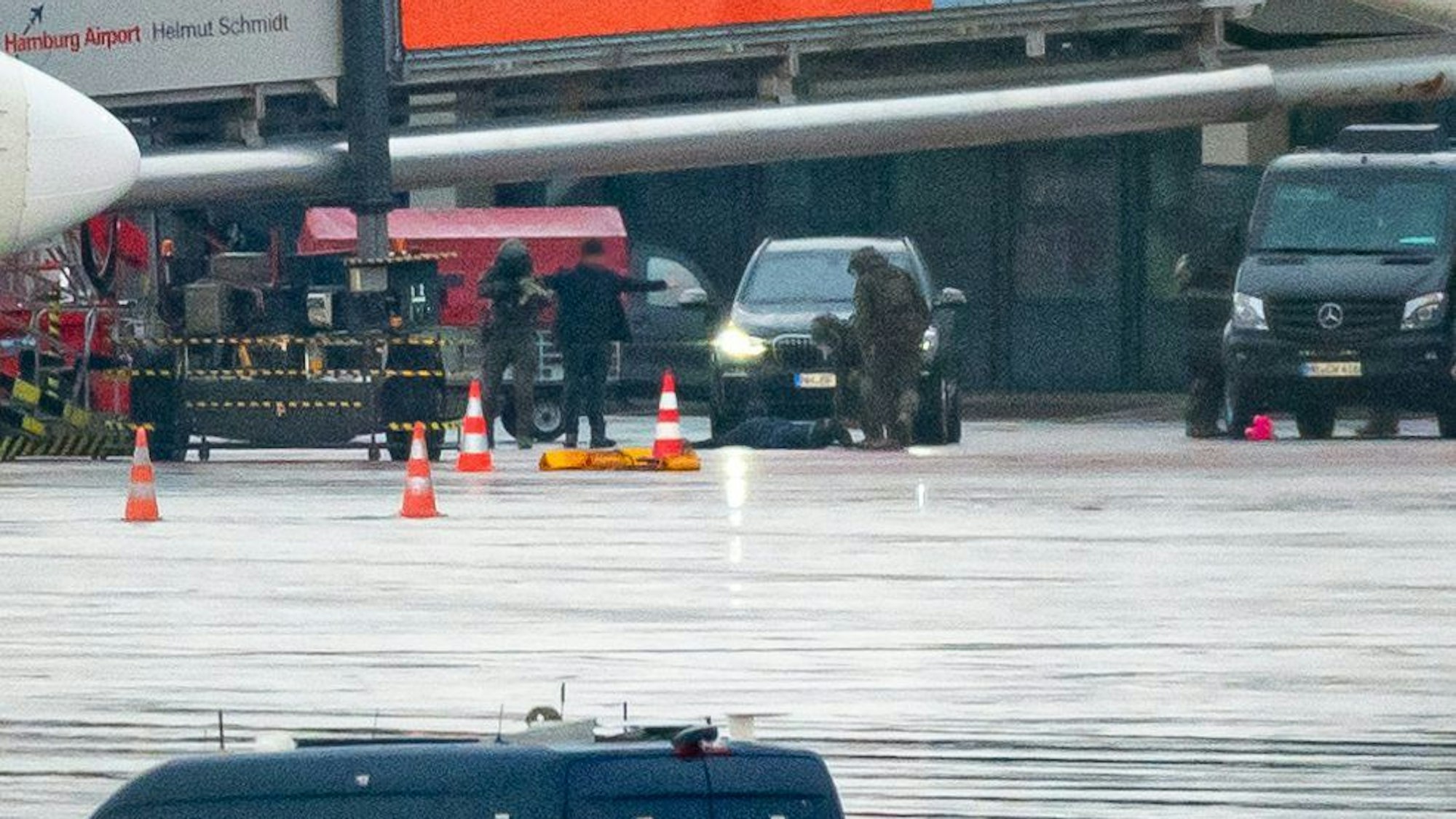 Der Geiselnehmer liegt am Flughafen vor einem Fahrzeug auf dem Boden und wird von Spezialkräften der Polizei in Schach gehalten.