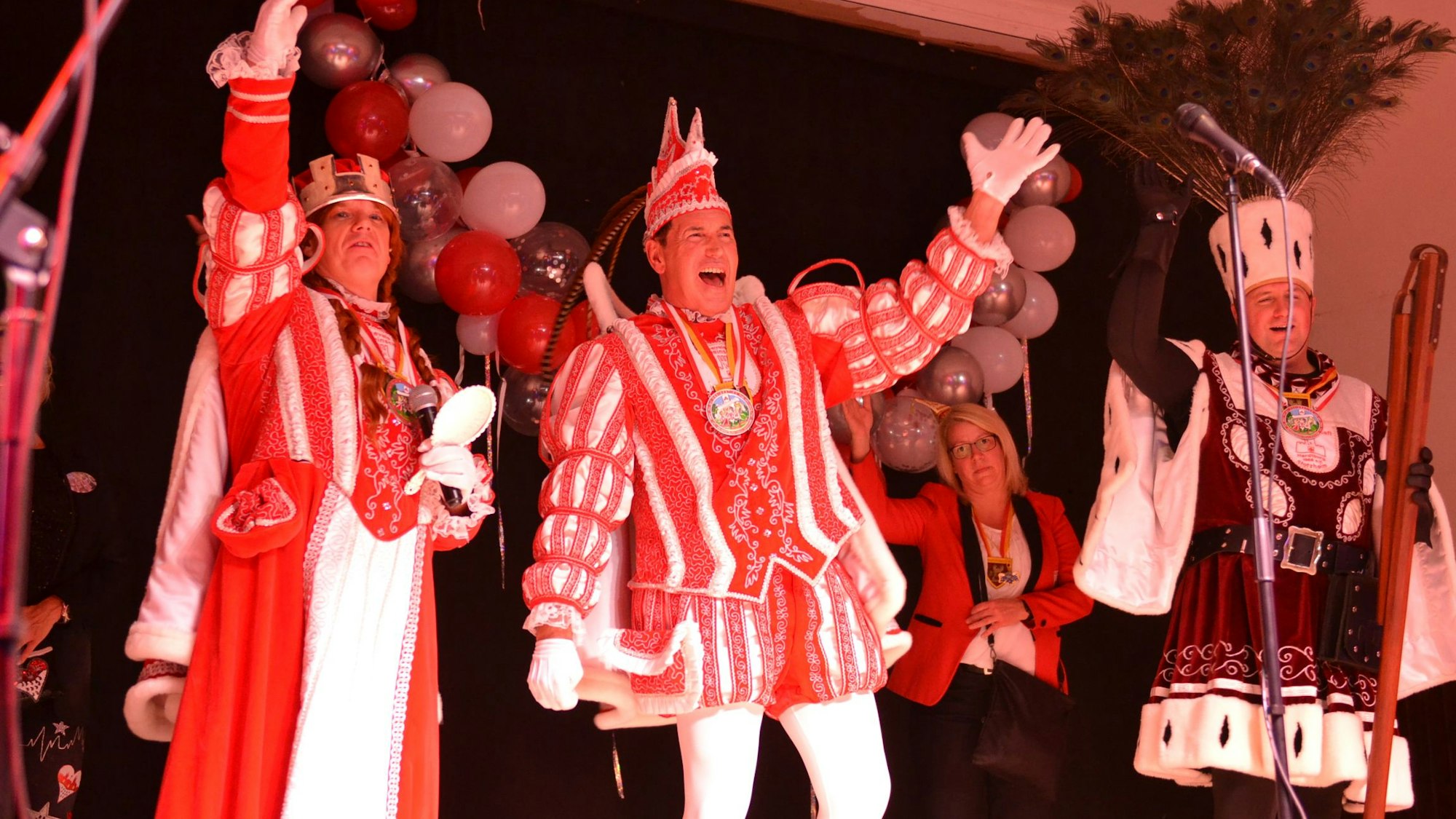 Das Bild zeigt das Stotzheimer Dreigestirn auf der Bühne. Die drei Karnevalisten sind gut gelaunt.