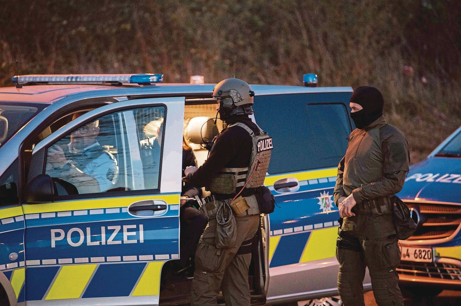 Auf dem Foto sind Mitglieder eines Spezialeinsatzkommandos zu sehen. Sie stehen an einem Polizeiwagen.