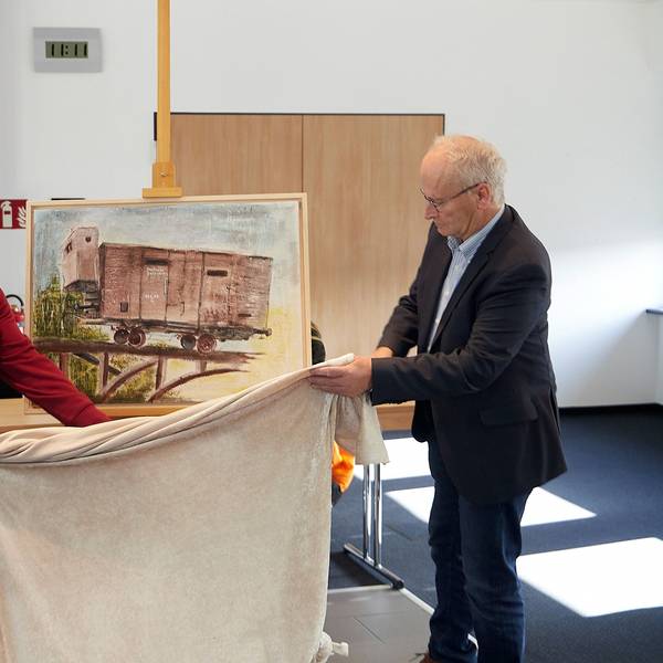 Rainer Schulz und Bürgermeister Dr. Hans-Peter Schick enthüllen im Mechernicher Ratssaal ein Bild, das an die Deportation der Juden erinnert.